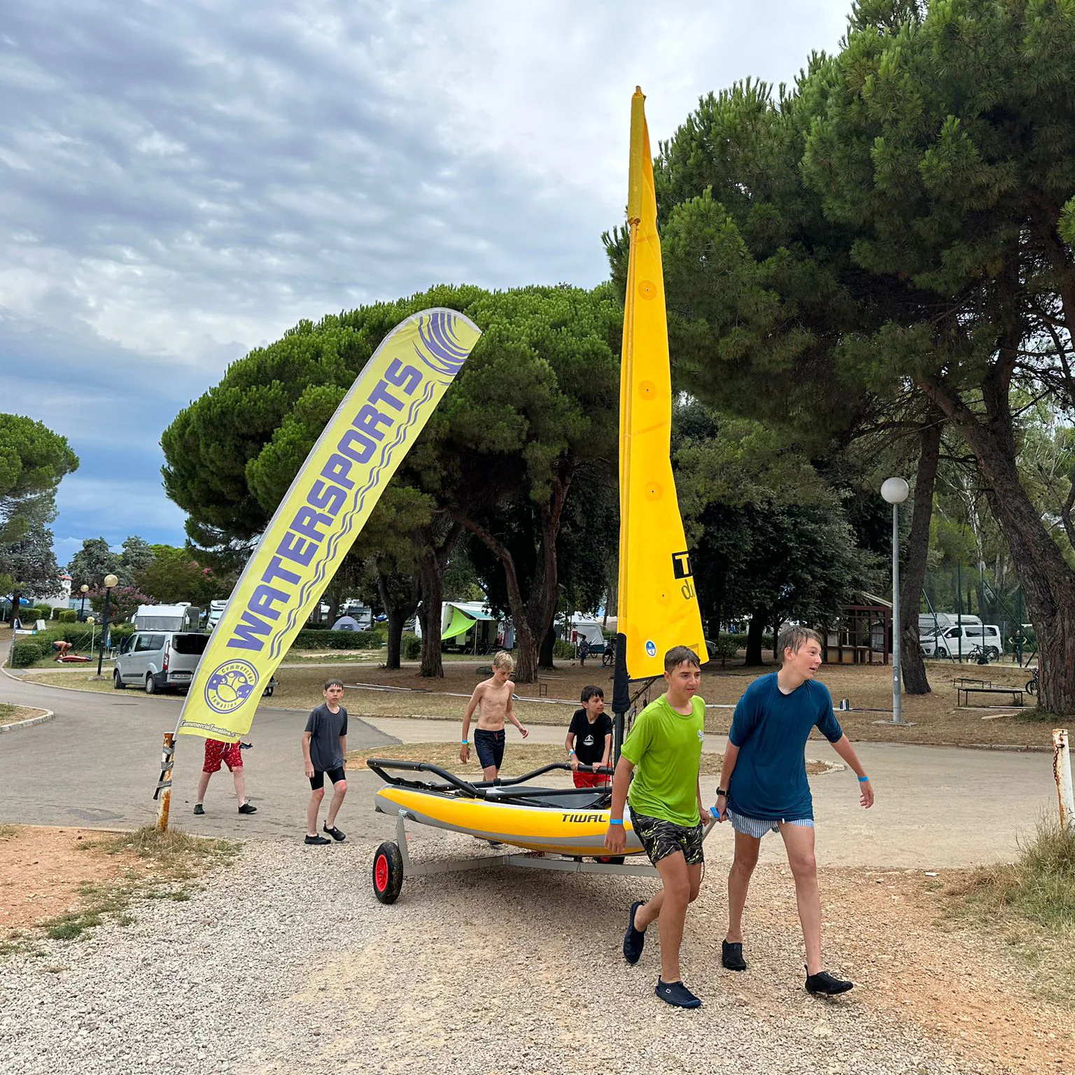 Kids moving their Tiwal Club sailing dinghy on the beach dolly