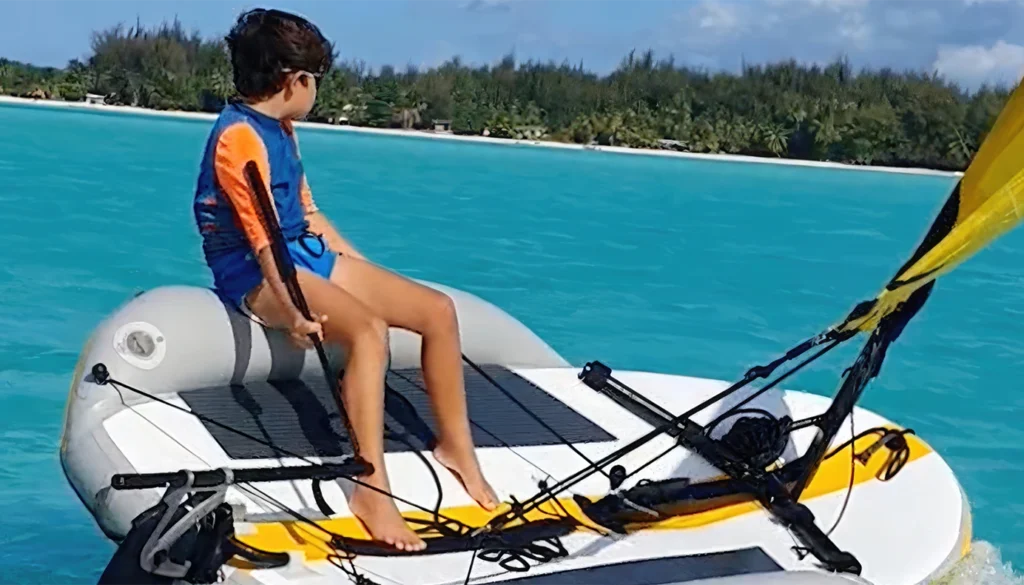 Kind segelt auf einem kleinen Segelboot auf Bora Bora